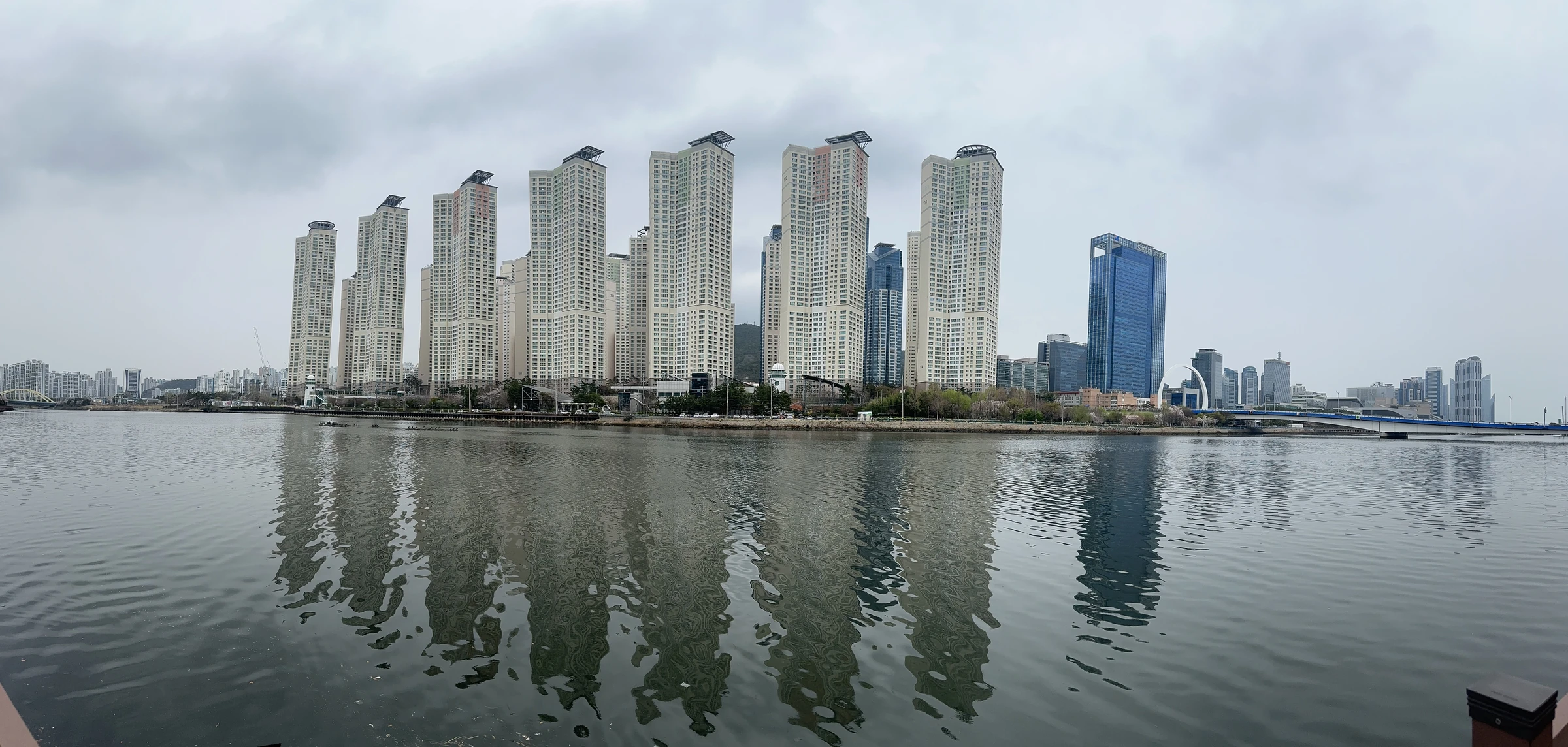 View across the Suyeong River path near Centum with apartment towers reflected in the river